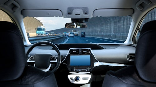 Image of the interior of a fully autonomous vehicle (AV) driving down a highway without a driver or passenger.